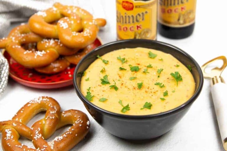 A bowl of pretzel dip with pretzels and beer.