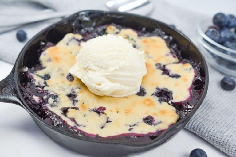 Sweet blueberry cobbler in a skillet with ice cream.