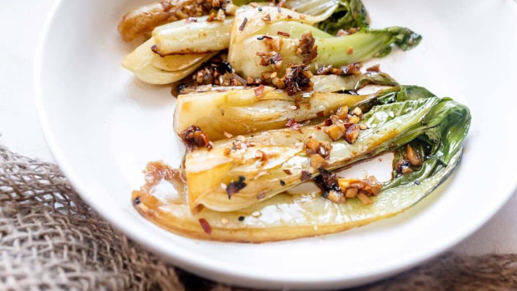 A white plate with grilled vegetables and nuts.