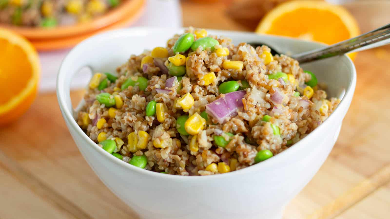 A bowl of bulgur and peas on a wooden table.