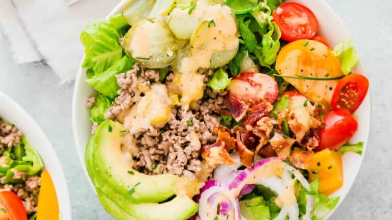 Two bowls of salad with lettuce, tomatoes, ground beef and avocados.