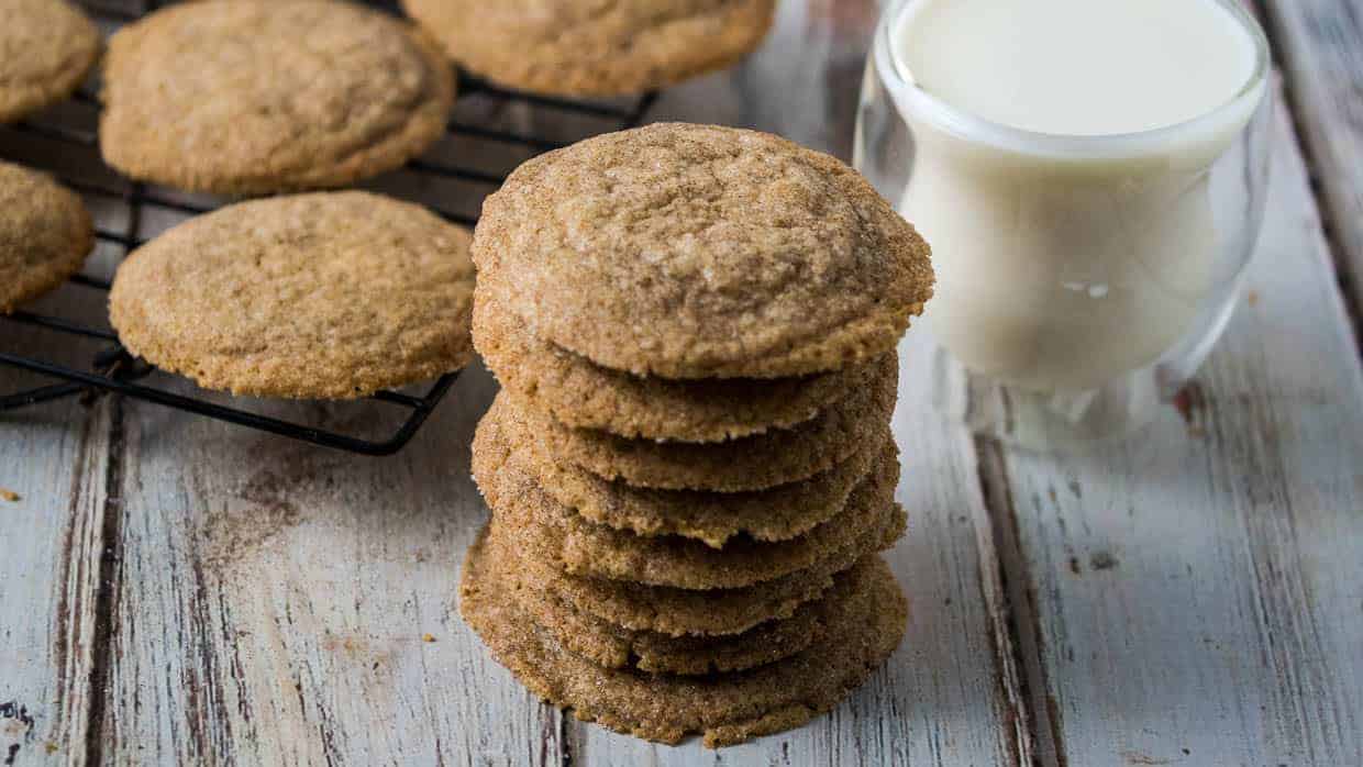 Stack of cardamom cookies with a glass of milk in the background.