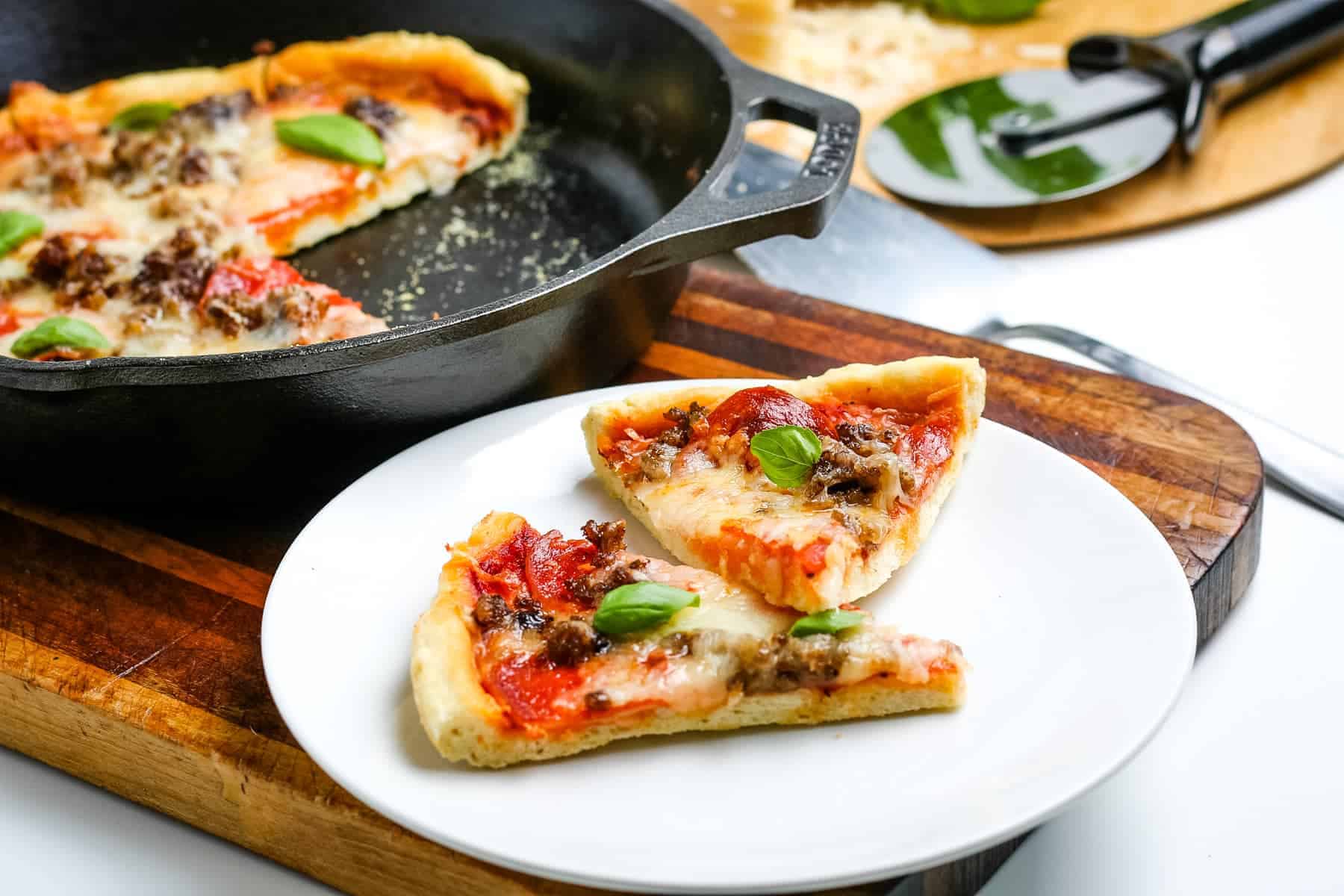 Two slices of cast iron skillet pizza on a white plate.