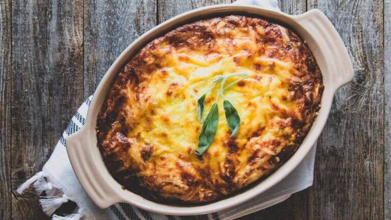 A casserole dish with a sprig of sage.