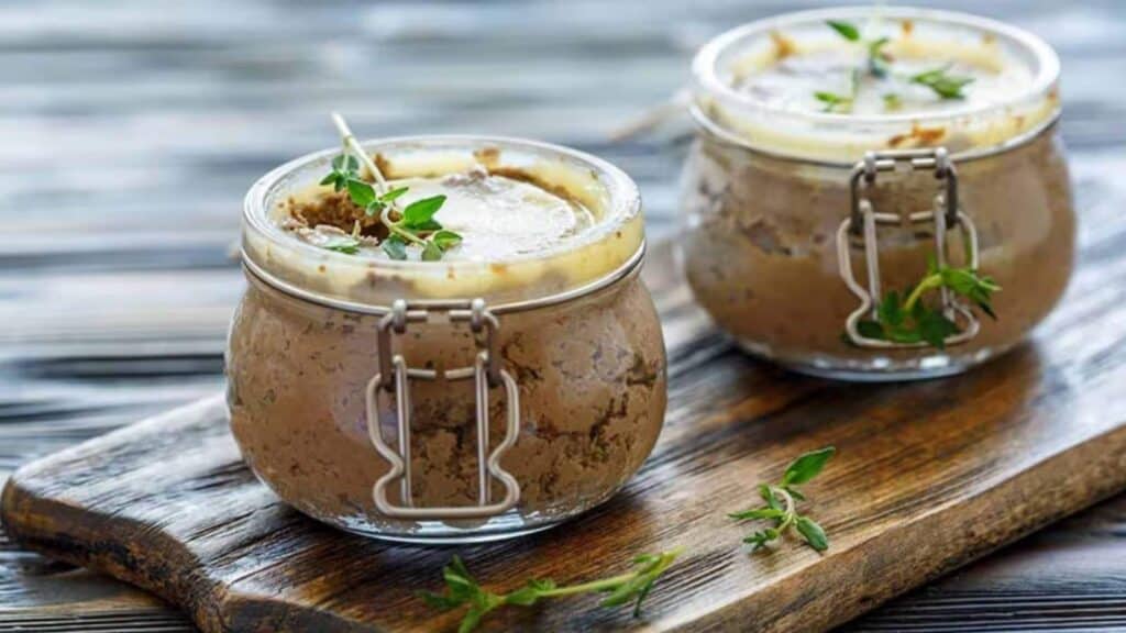 Beef liver pate in jars on wood.