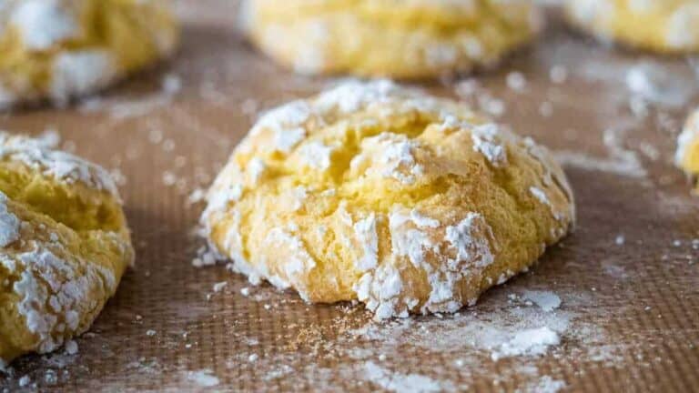 Powdered sugar covered cookies on a baking sheet.