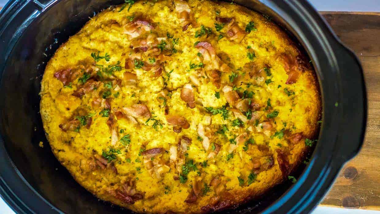 Top view of crock pot cornbread dressing with bacon and parsley on top.