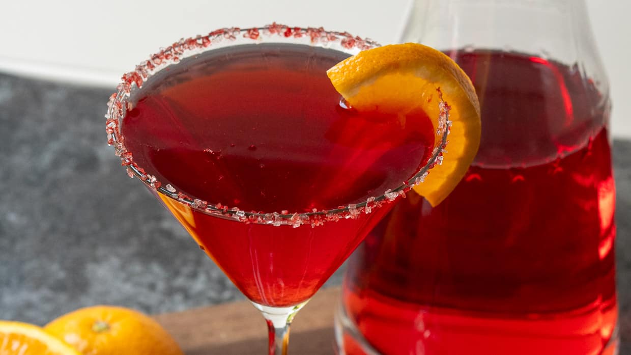 A martini in a glass with a slice of orange.