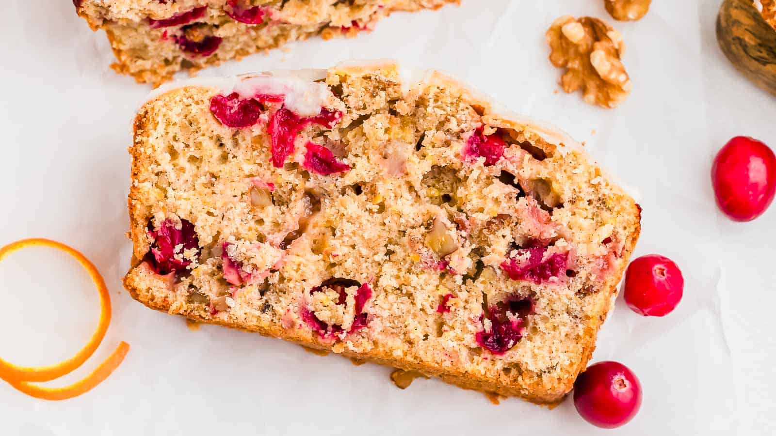 A slice of cranberry bread with cranberries and nuts.