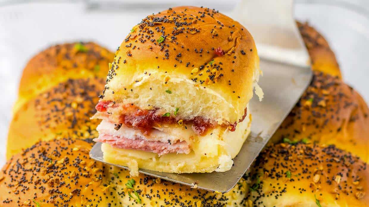 Cranberry turkey sliders on a plate next to a jar of cranberry sauce.