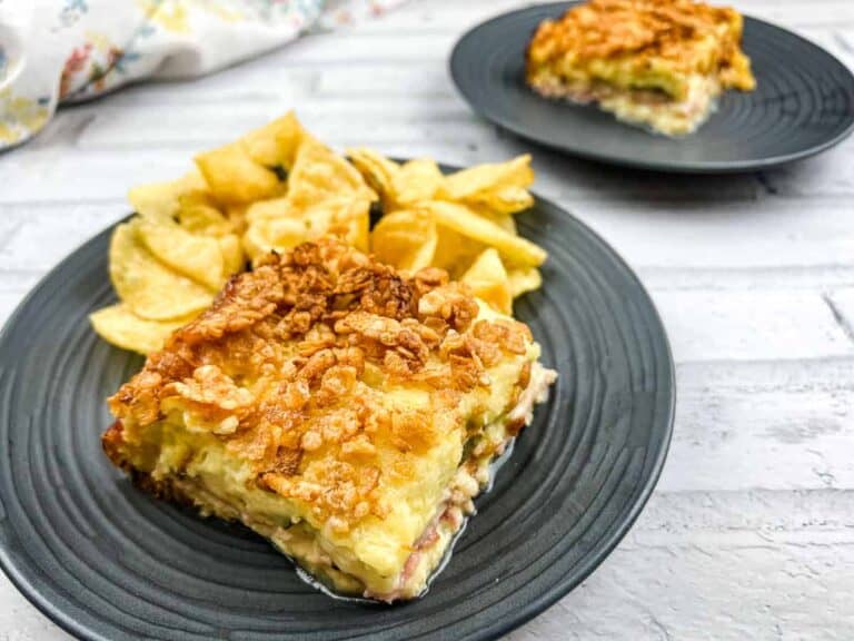 A piece of Cuban sandwich casserole on a plate with potato chips.