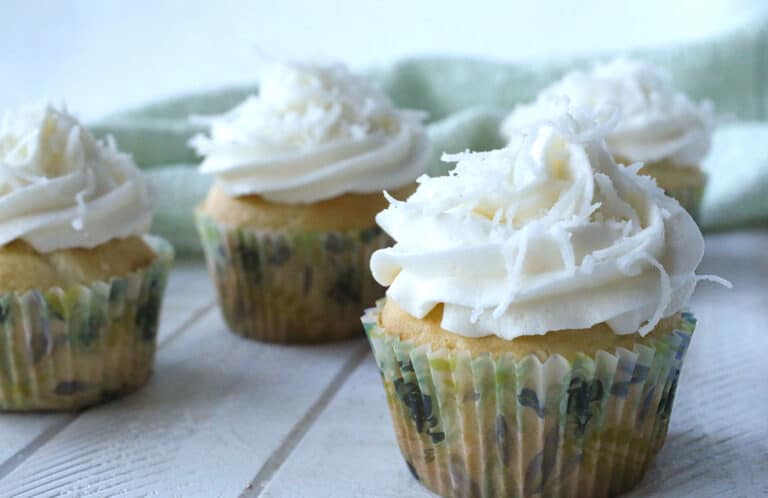 Coconut cupcakes with whipped cream and coconut flakes.