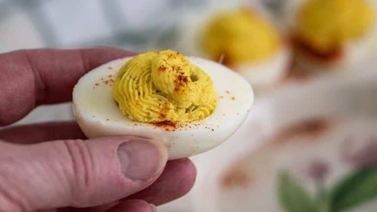 A person holding deviled eggs on a plate.