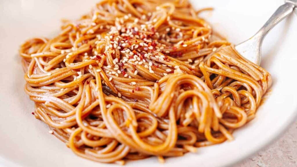 A bowl of noodles with sesame seeds and sesame oil, prepared using five star recipes.