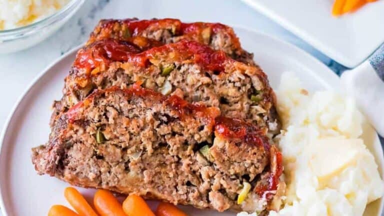 Meatloaf on a plate with carrots and mashed potatoes.
