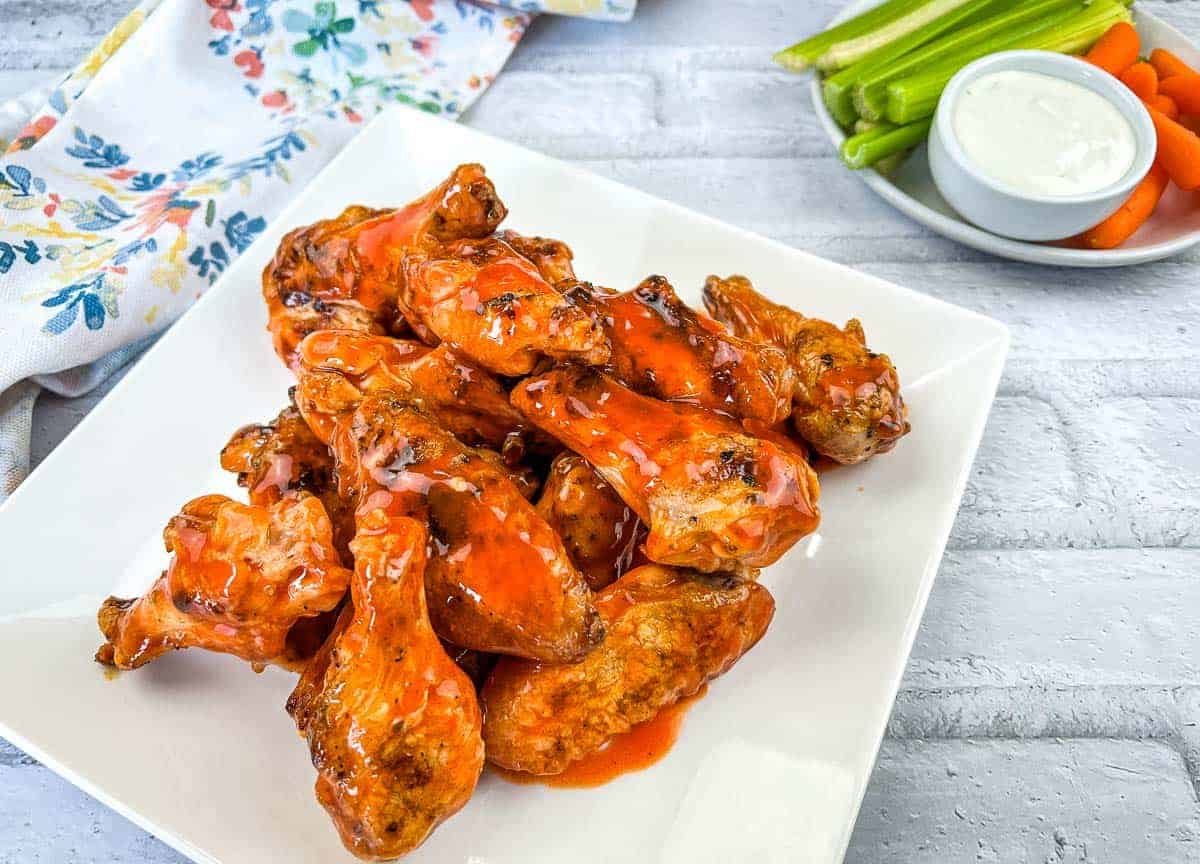 A plate of grilled wings with buffalo sauce.