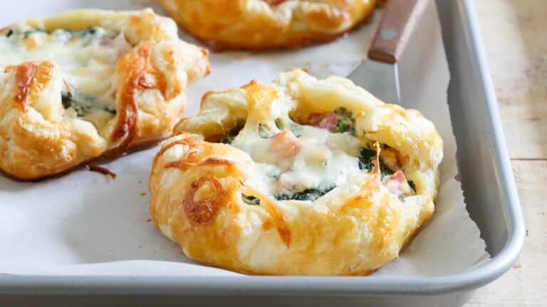 A tray of pastries with cheese and spinach on it.