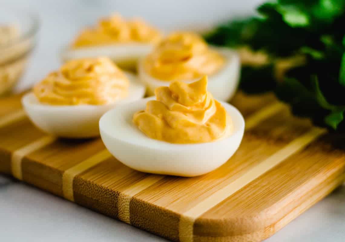 A batch of hummus deviled eggs on a serving board.