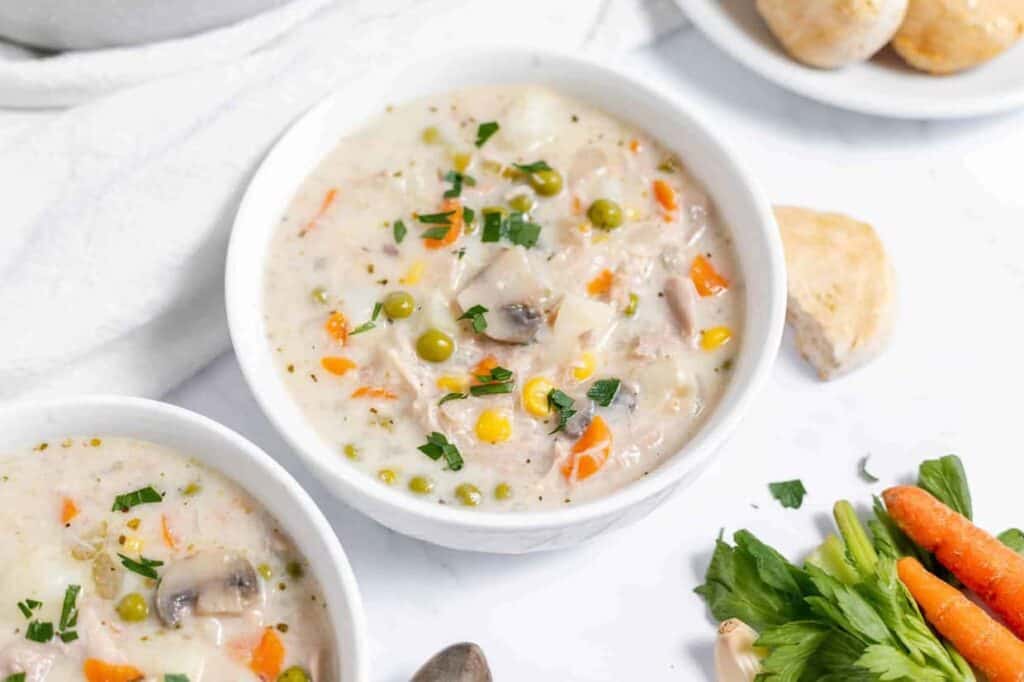 Two bowls of chicken chowder with carrots and potatoes.