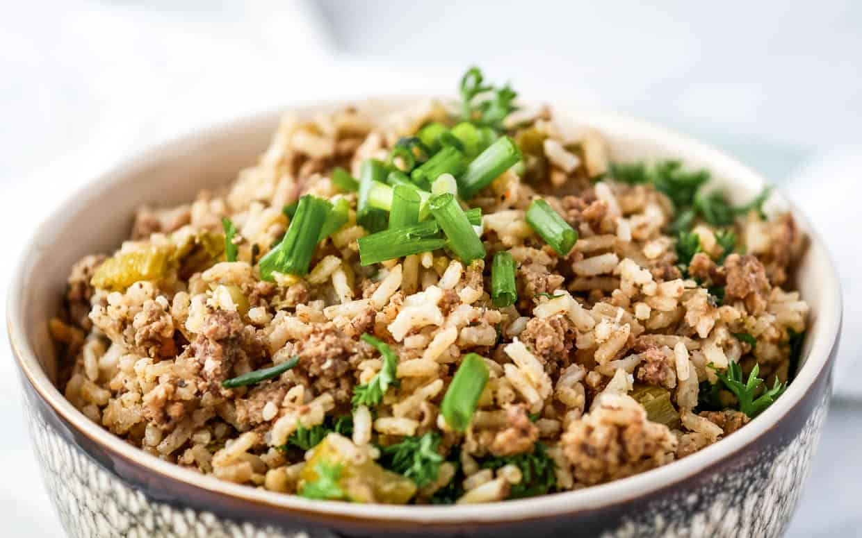 A bowl of rice with meat and green onions.