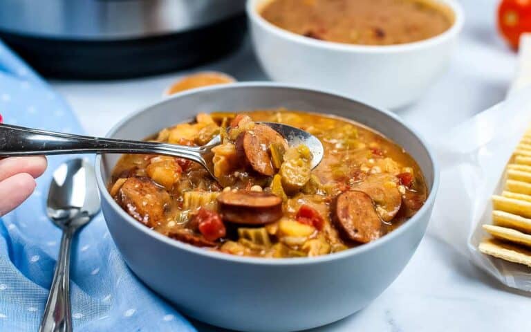 A bowl of gumbo in front of an instant pot.