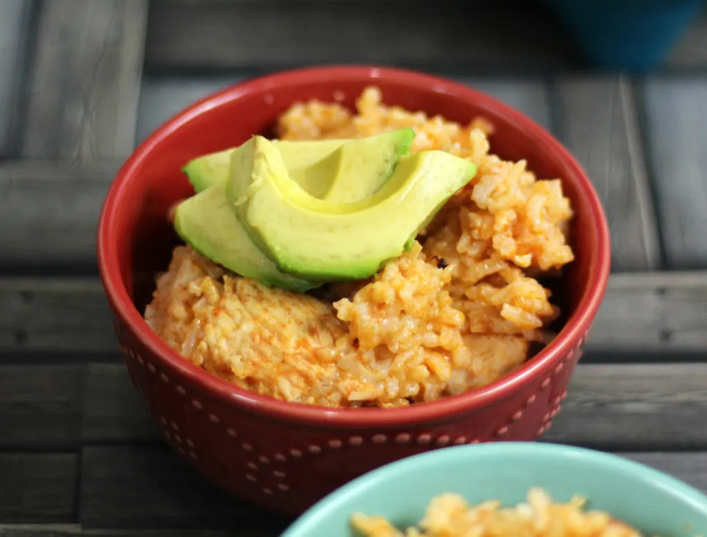 Two bowls of mexican rice with avocado on top.