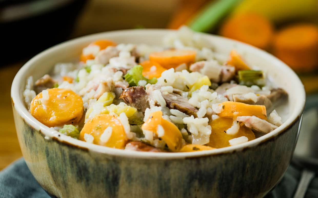 A bowl of rice with carrots and meat in it.