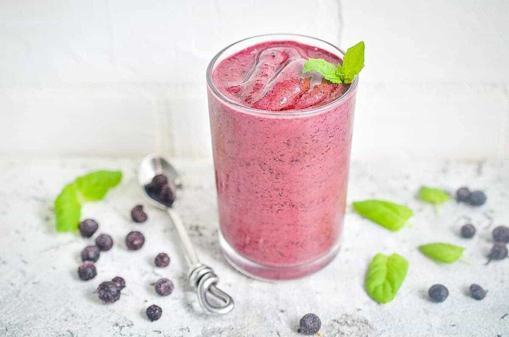 An easy blueberry smoothie in a glass with mint leaves, perfect for a refreshing breakfast.