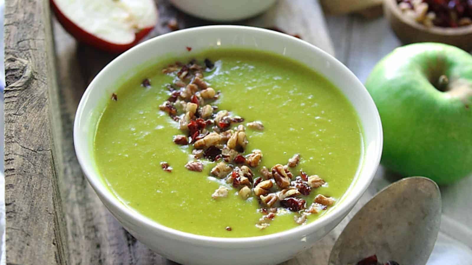 A bowl of apple cheddar leek soup with chopped nuts.