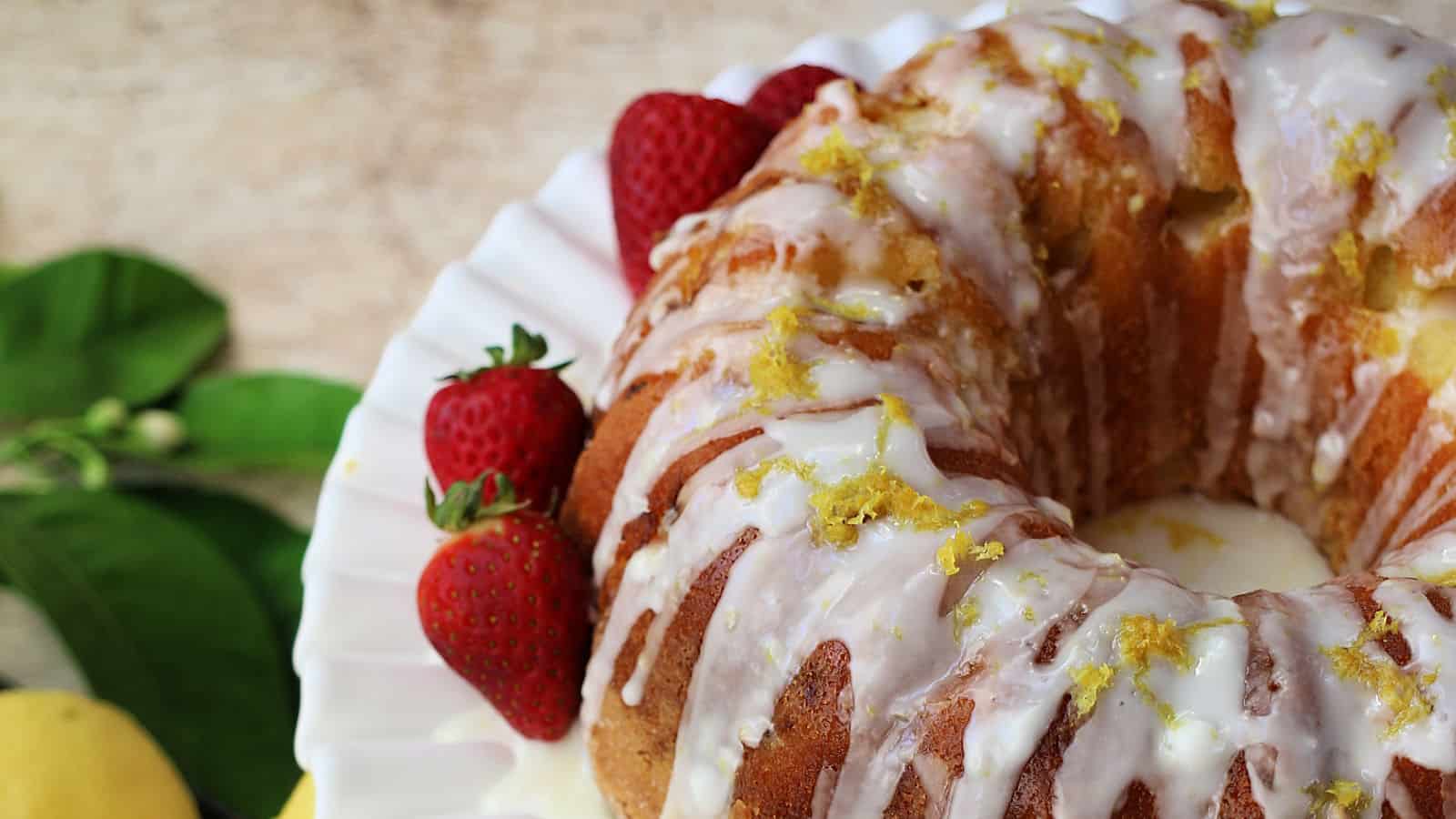 Lemon bundt cake on a white plate with strawberries.