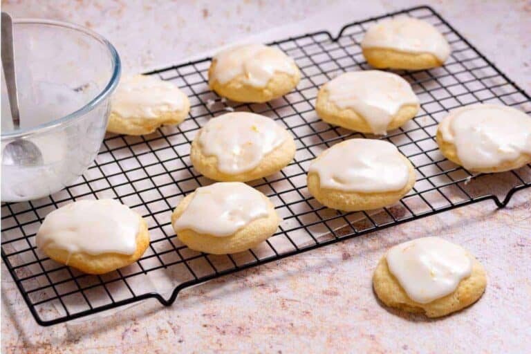 Lemon icing cookies on a cooling rack with a glass of milk.