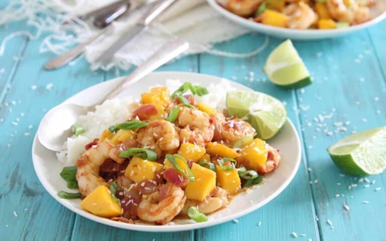 A bowl of rice with shrimp and mangoes.