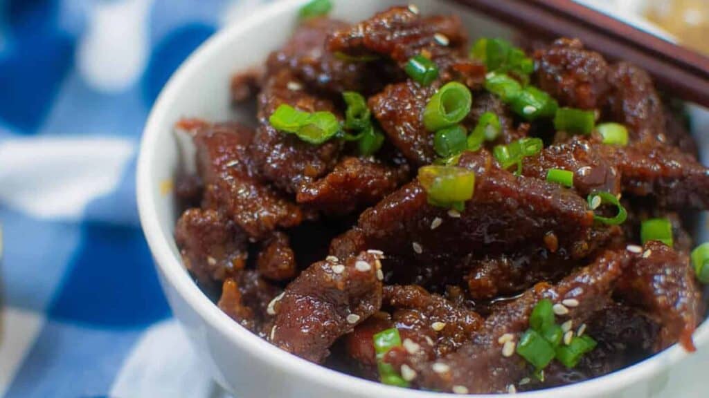 A bowl of meat in a bowl with chopsticks.