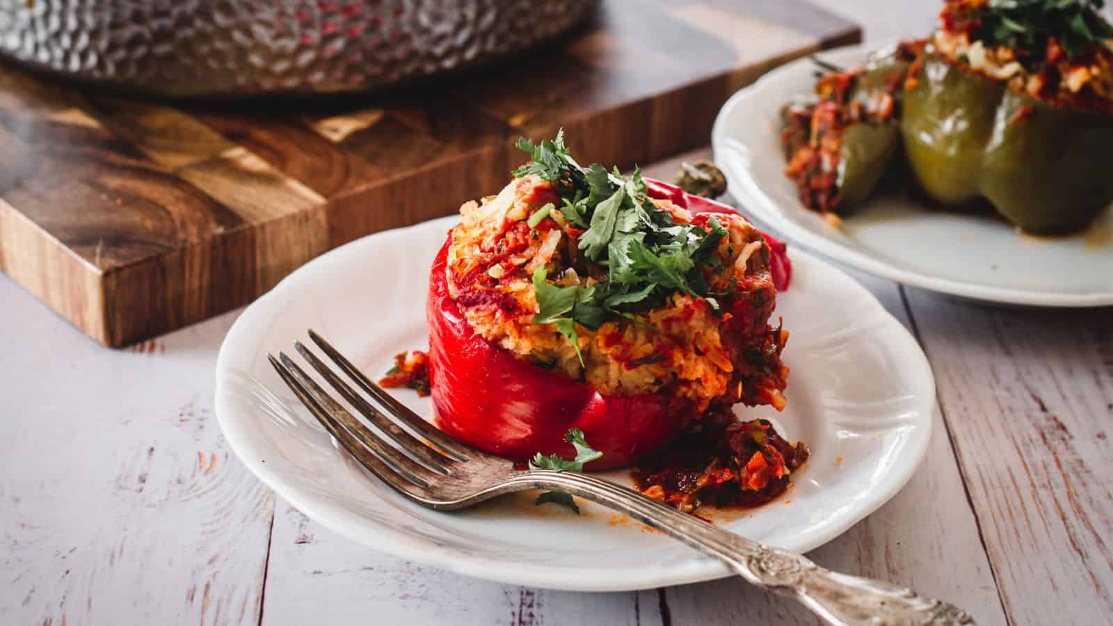 one stuffed pepper on plate with pot in background.