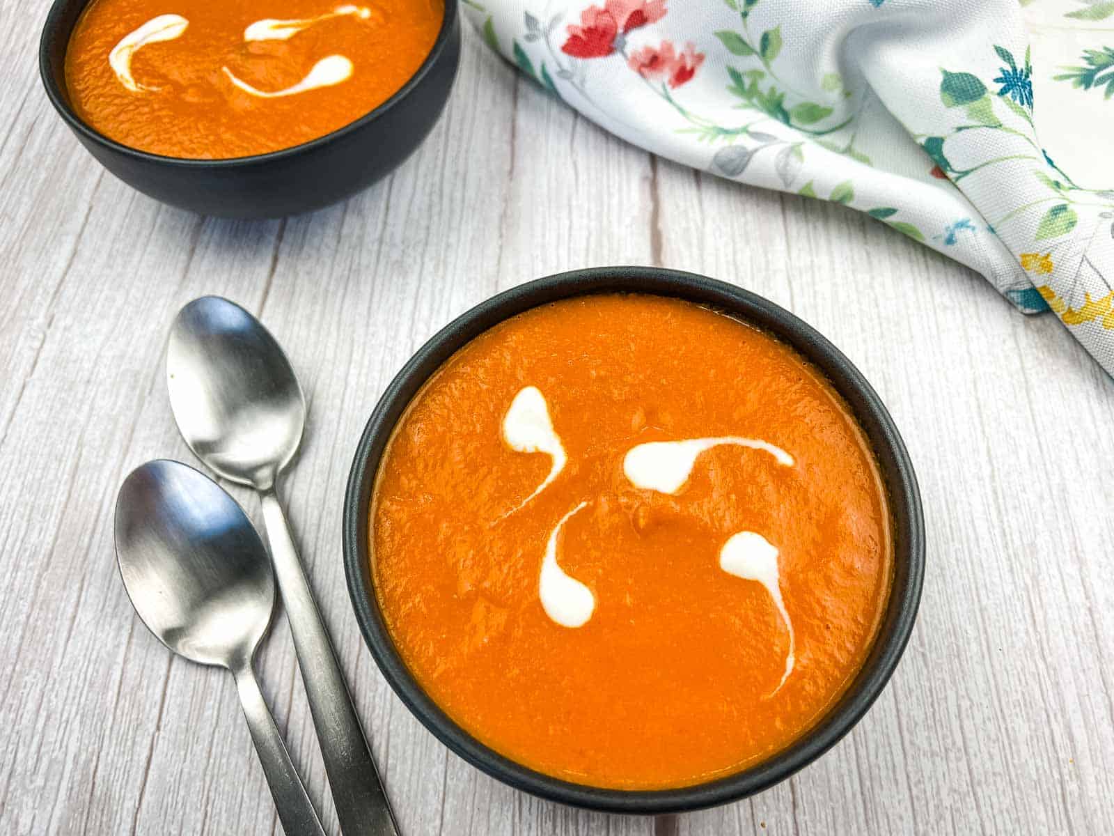 A bowl of oven-roasted tomato soup with two spoons.