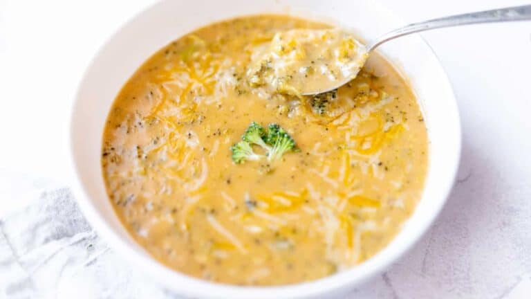 A bowl of broccoli cheese soup with a spoon, prepared using a five star recipe.