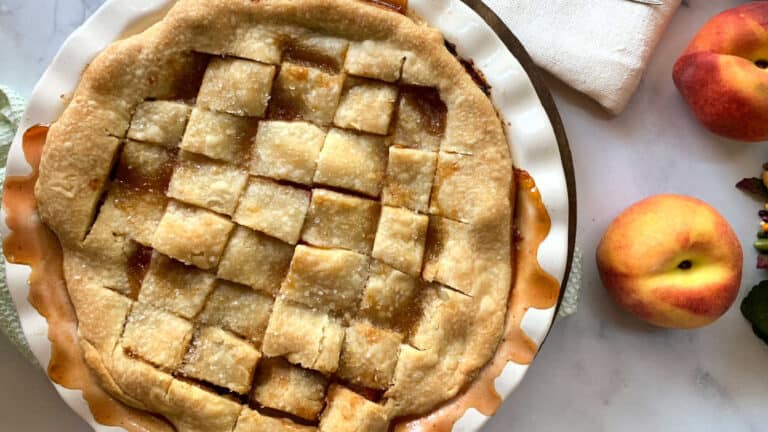 Peach pie with lattice topping on a white plate.