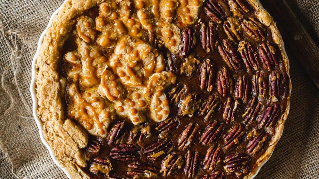 A pecan pie with caramel drizzle.
