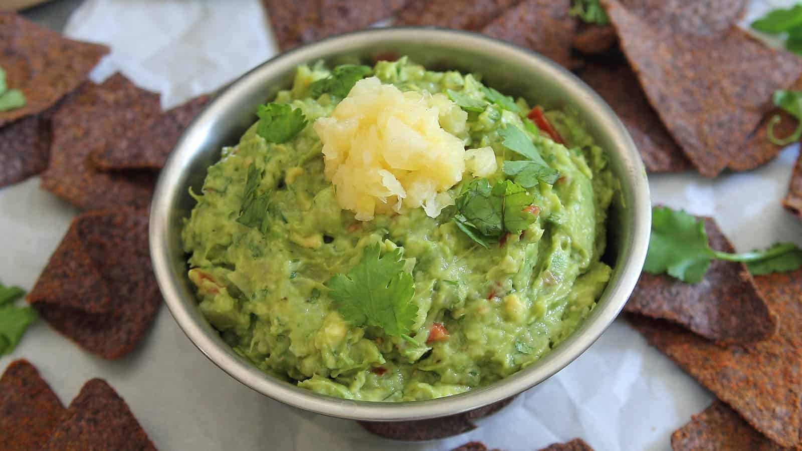 Pineapple guacamole in a metal bowl topped with crushed pineapple.