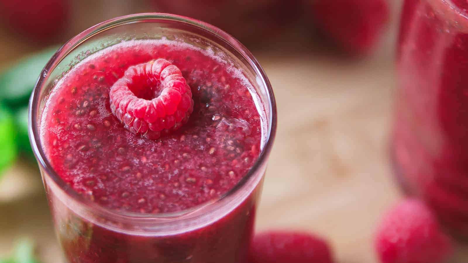 Raspberry chia lemonade in a glass garnished with a raspberry.