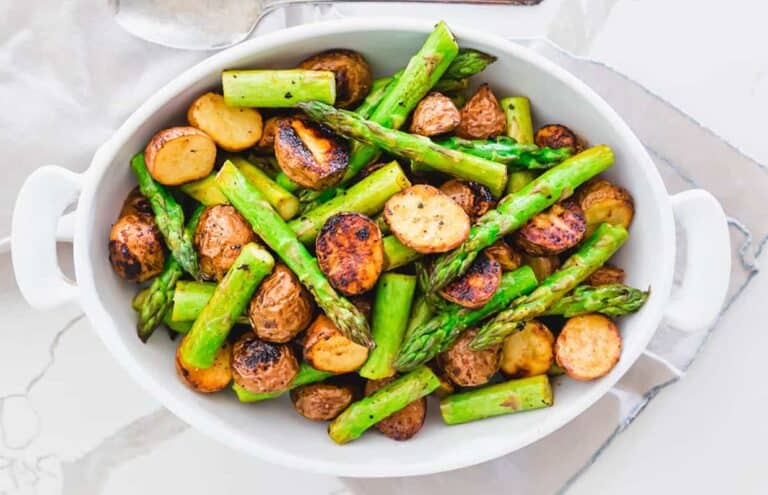 Roasted asparagus and potatoes in a white bowl.