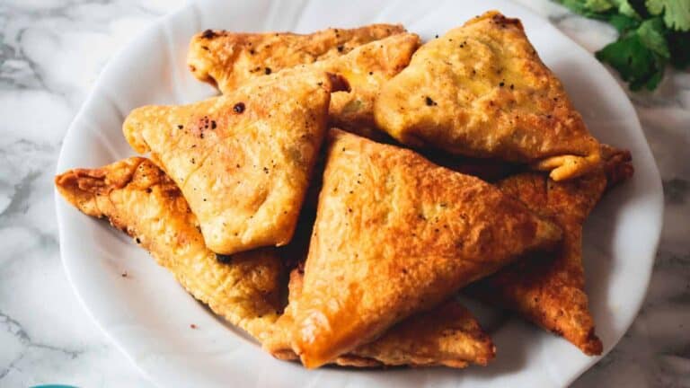 A plate of fried samosas on a marble table.