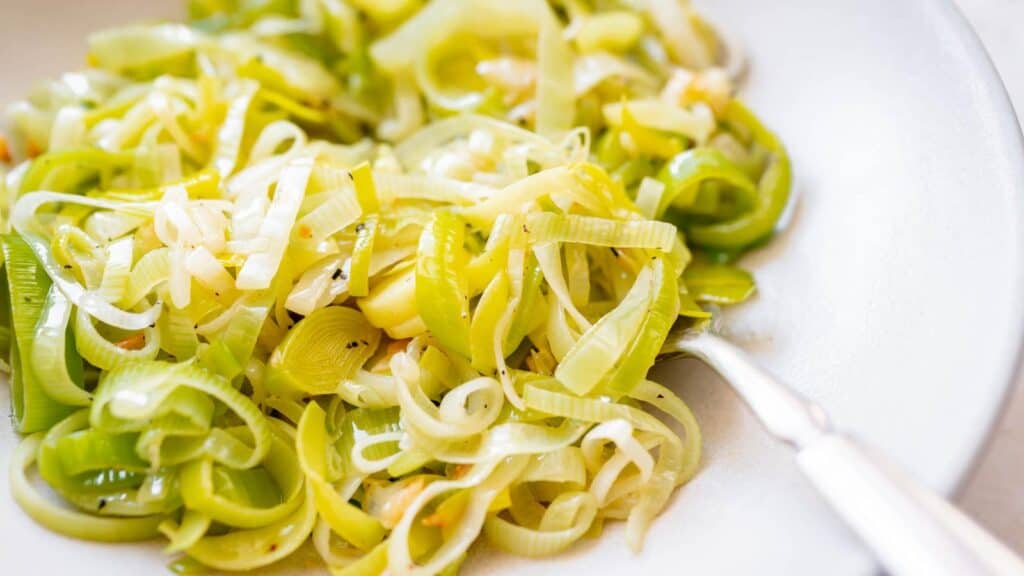 A white plate with green vegetables and a fork.