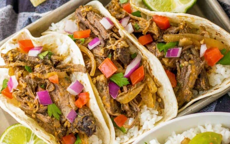 Three beef tacos on a tray with rice.