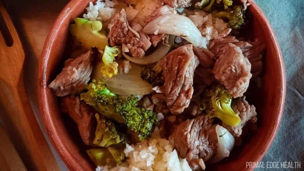 A bowl of rice with meat and broccoli in it.