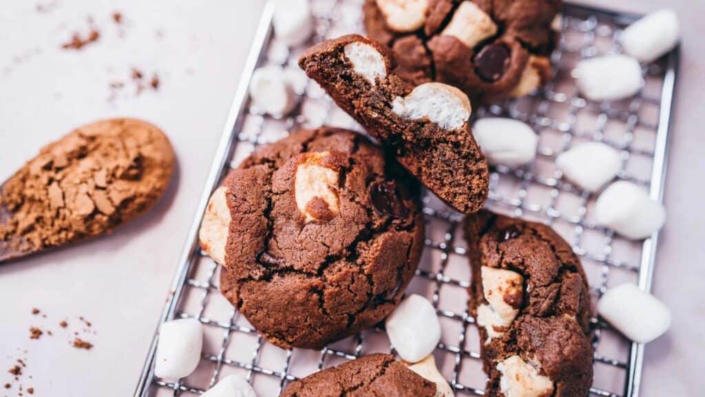 Gluten-free chocolate cookies with marshmallows cooling on a rack.