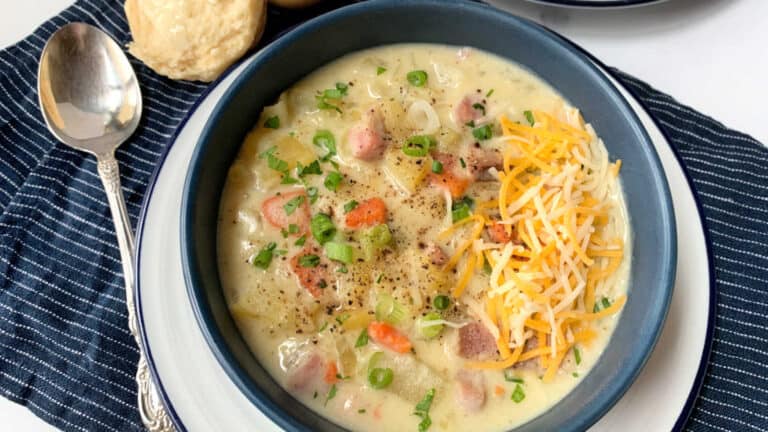 A blue bowl of ham and potato soup.