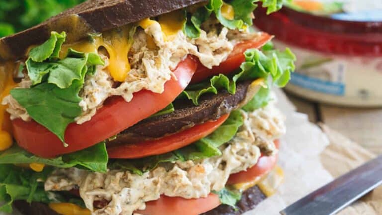 A sandwich with chicken salad, tomatoes and lettuce.