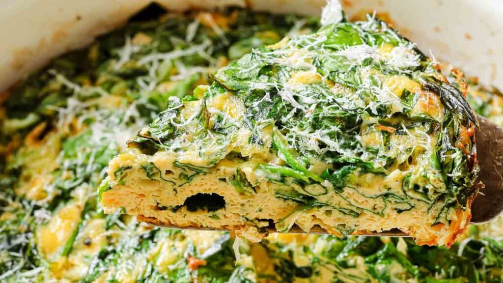 A slice of quiche with spinach and parmesan.