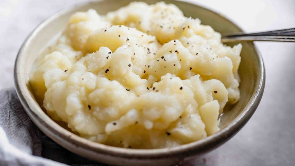 Mashed potatoes in a bowl with a spoon.